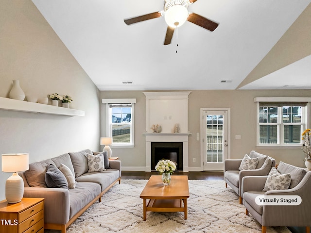 living room with a wealth of natural light, vaulted ceiling, ceiling fan, and hardwood / wood-style flooring