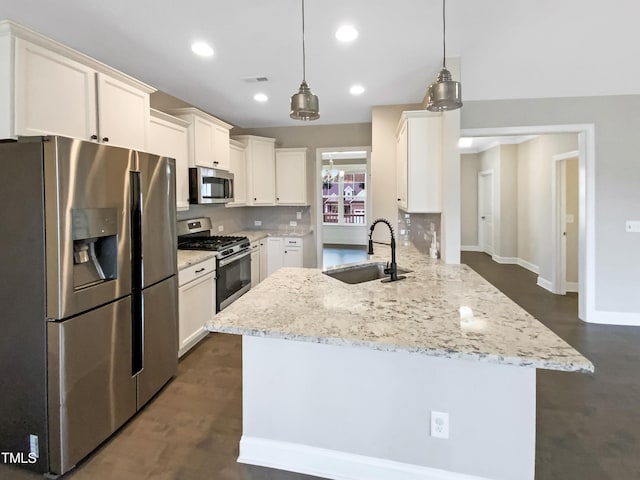 kitchen featuring appliances with stainless steel finishes, sink, light stone counters, and decorative light fixtures