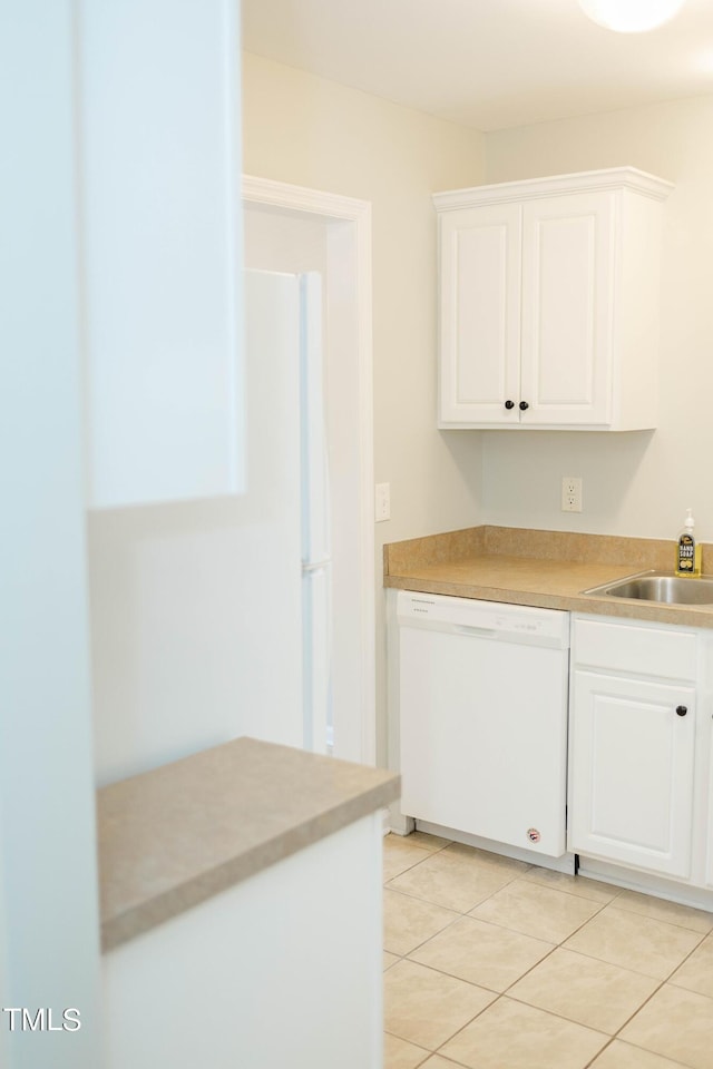 kitchen with light tile patterned flooring, white dishwasher, sink, and white cabinets