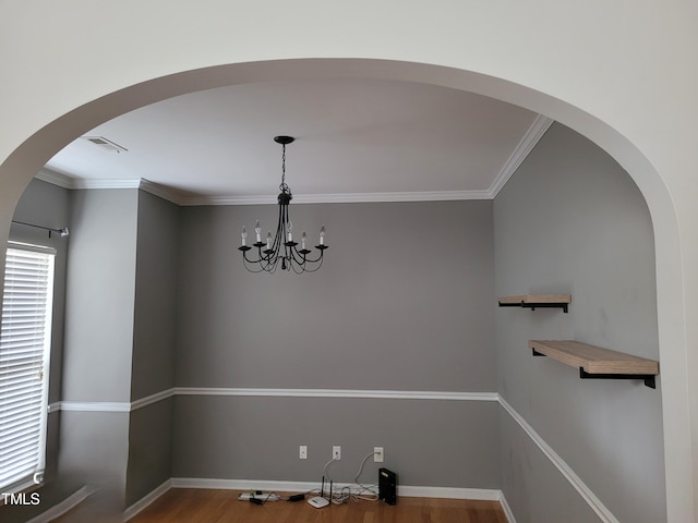 unfurnished dining area with crown molding, hardwood / wood-style flooring, and a chandelier