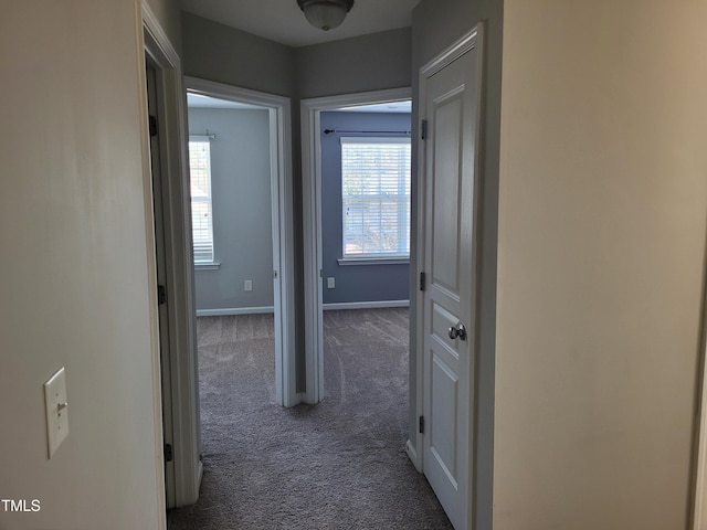 corridor with plenty of natural light and dark colored carpet