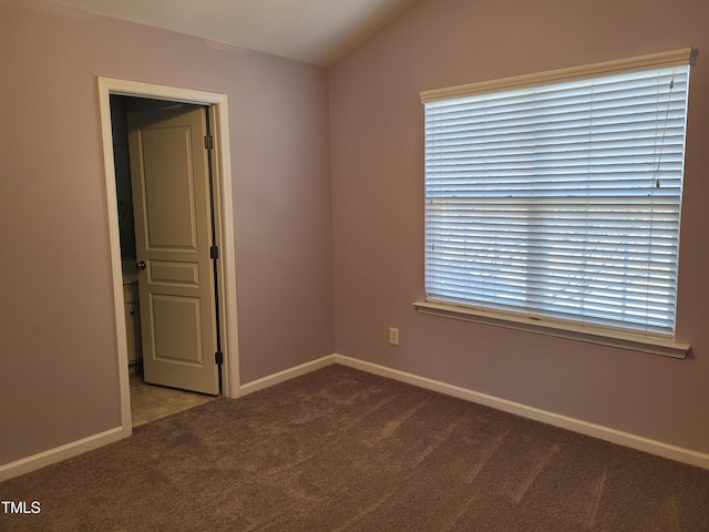 carpeted empty room with vaulted ceiling