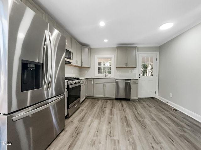 kitchen with gray cabinets, appliances with stainless steel finishes, sink, and light hardwood / wood-style flooring