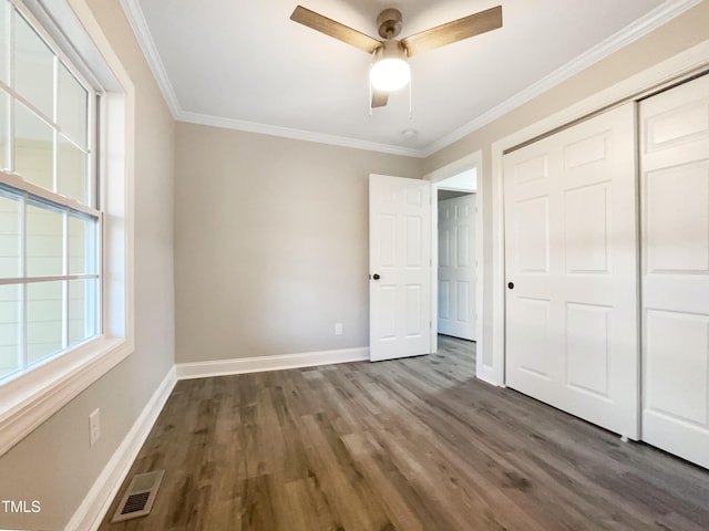 unfurnished bedroom with crown molding, ceiling fan, dark wood-type flooring, and a closet