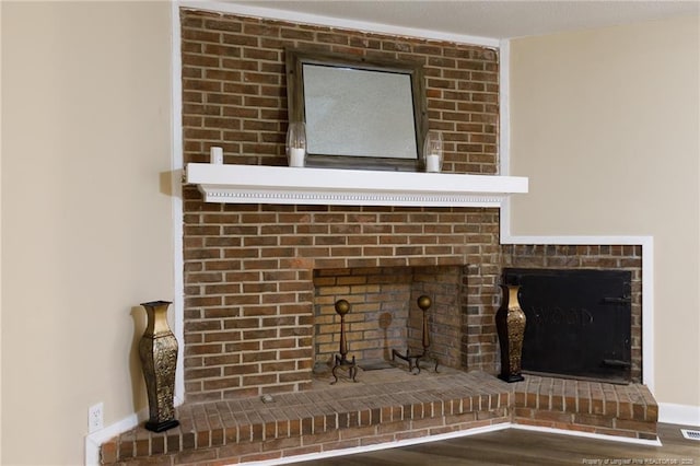 interior details with wood-type flooring and a brick fireplace