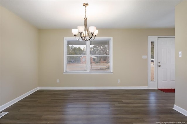 unfurnished dining area featuring an inviting chandelier and dark hardwood / wood-style flooring