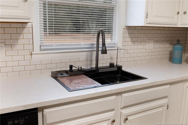 kitchen featuring tasteful backsplash, sink, white cabinetry, and dishwasher