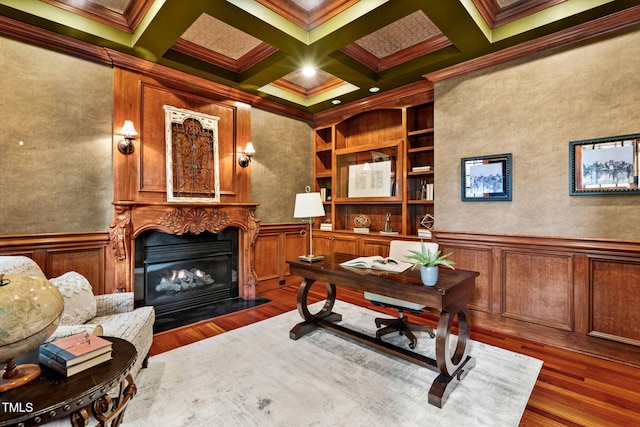 home office with built in shelves, dark wood-type flooring, coffered ceiling, ornamental molding, and beam ceiling