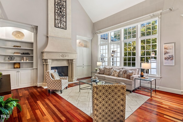 living room with a high end fireplace, light wood-type flooring, and a wealth of natural light