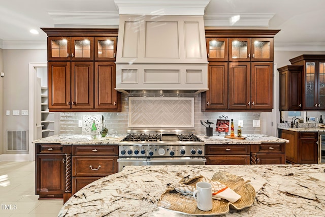 kitchen featuring double oven range, backsplash, ornamental molding, and light stone countertops