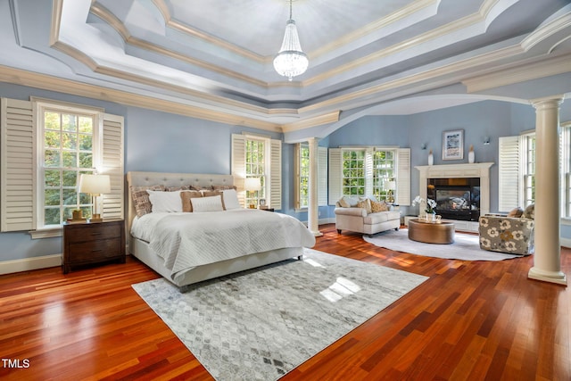 bedroom featuring ornate columns, crown molding, multiple windows, and a tray ceiling