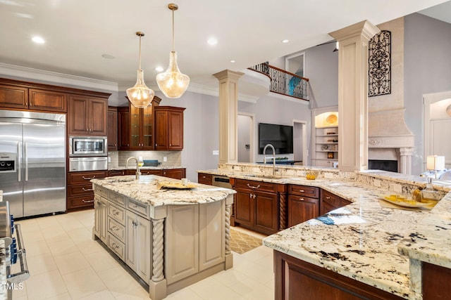 kitchen with sink, backsplash, a large island with sink, built in appliances, and light stone countertops