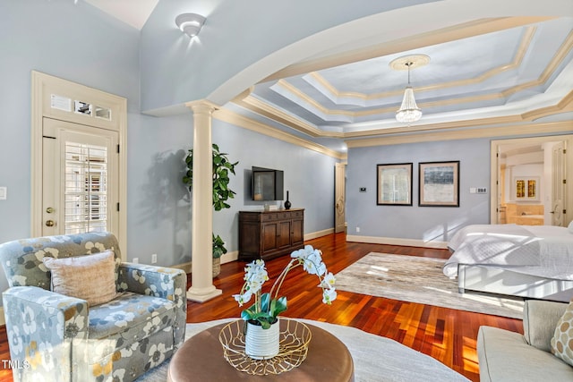 interior space featuring a tray ceiling, ornamental molding, dark hardwood / wood-style floors, and ornate columns