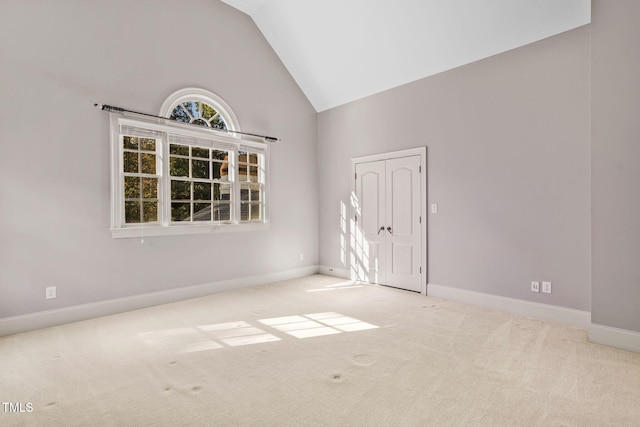 spare room with light carpet and high vaulted ceiling