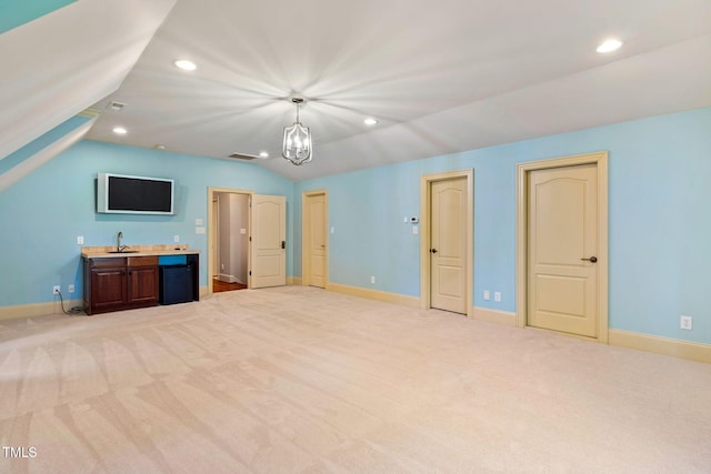 unfurnished bedroom with sink, a notable chandelier, vaulted ceiling, and light colored carpet