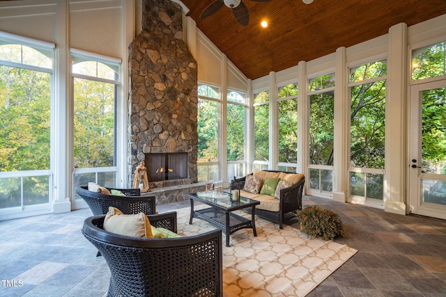 sunroom / solarium with a stone fireplace, a wealth of natural light, and wooden ceiling