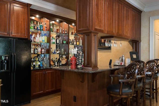 bar featuring black fridge, crown molding, and dark stone countertops