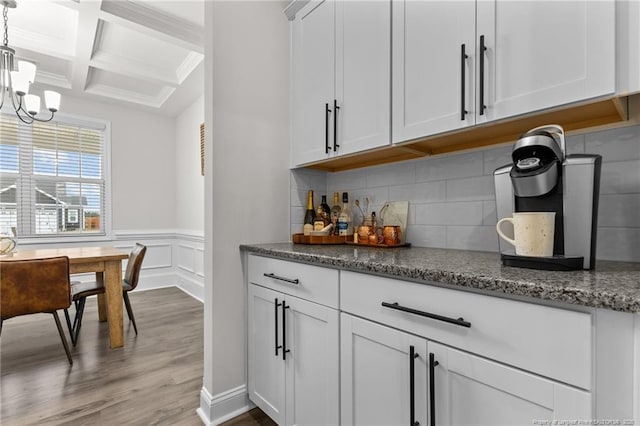 bar featuring coffered ceiling, decorative light fixtures, beamed ceiling, light hardwood / wood-style floors, and white cabinets