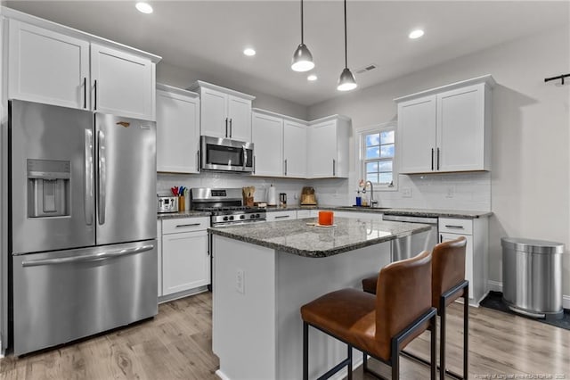 kitchen with white cabinetry, sink, hanging light fixtures, and appliances with stainless steel finishes