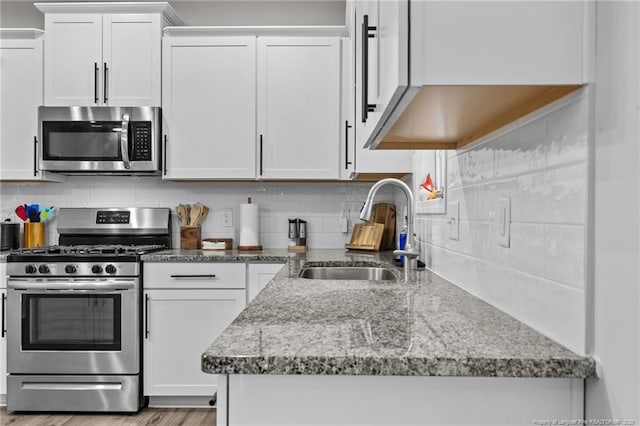 kitchen featuring white cabinetry, sink, backsplash, stainless steel appliances, and light stone countertops