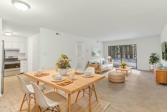 dining space with light wood finished floors and visible vents