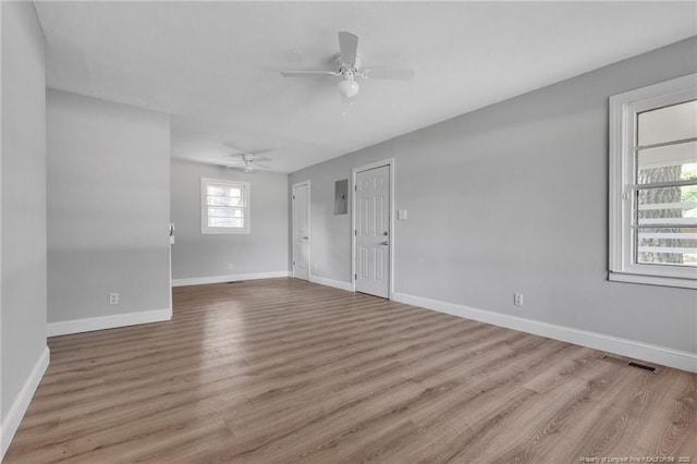 spare room with ceiling fan, plenty of natural light, electric panel, and light hardwood / wood-style floors