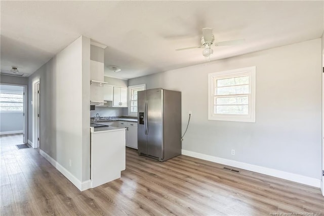 kitchen featuring white cabinetry, a wealth of natural light, stainless steel fridge, and light hardwood / wood-style flooring