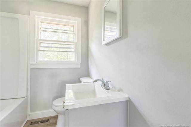 bathroom with hardwood / wood-style flooring, vanity, a washtub, and toilet