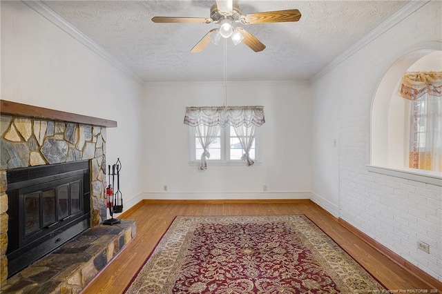 living room with a fireplace, light hardwood / wood-style flooring, ornamental molding, and a textured ceiling