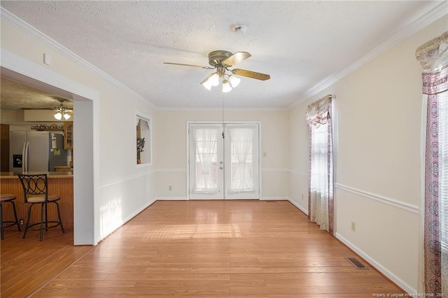 interior space featuring ornamental molding, french doors, ceiling fan, and light wood-type flooring