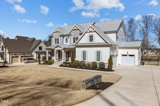 view of front facade with roof with shingles, fence, a garage, stone siding, and driveway