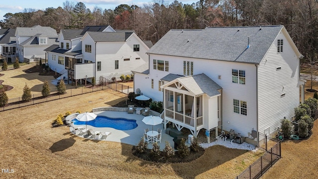 rear view of property featuring a fenced in pool, roof with shingles, a sunroom, a residential view, and a fenced backyard