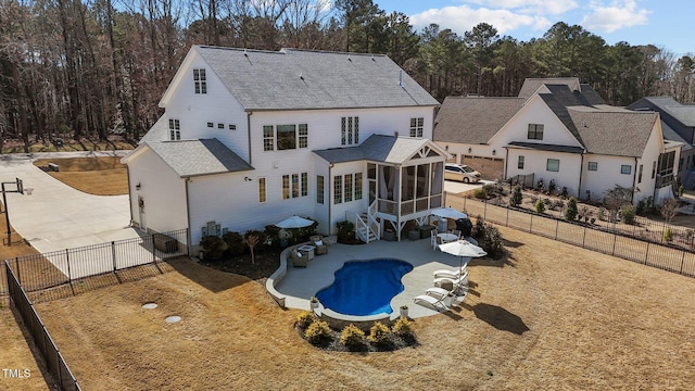 rear view of property with a fenced in pool, a patio, a shingled roof, a sunroom, and a fenced backyard