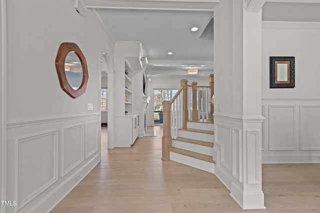 entryway with light wood finished floors, stairs, and a decorative wall