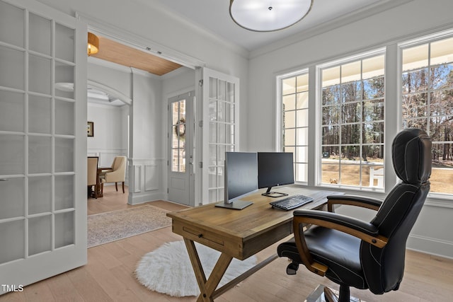 office space featuring a wainscoted wall, crown molding, a decorative wall, and wood finished floors