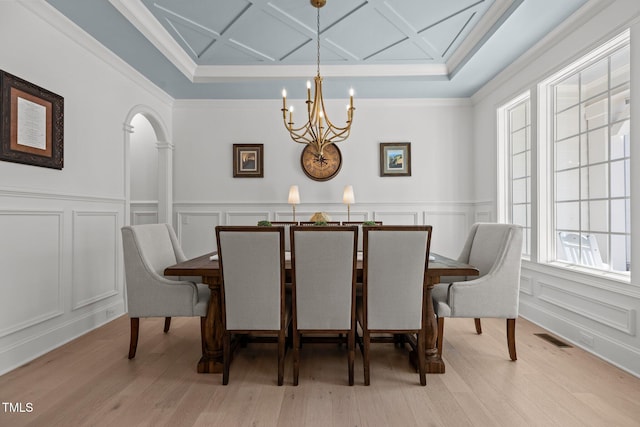 dining room featuring arched walkways, a notable chandelier, a decorative wall, coffered ceiling, and visible vents