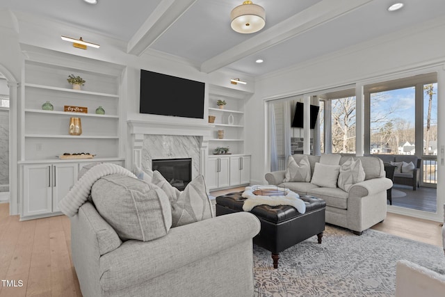 living room with a premium fireplace, beamed ceiling, light wood-style floors, built in shelves, and recessed lighting