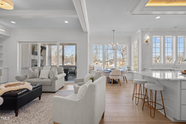 living room with ornamental molding, light wood finished floors, a wealth of natural light, and a notable chandelier