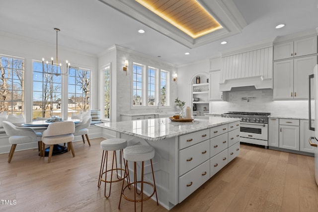 kitchen featuring premium range hood, ornamental molding, light wood-style flooring, and high end range