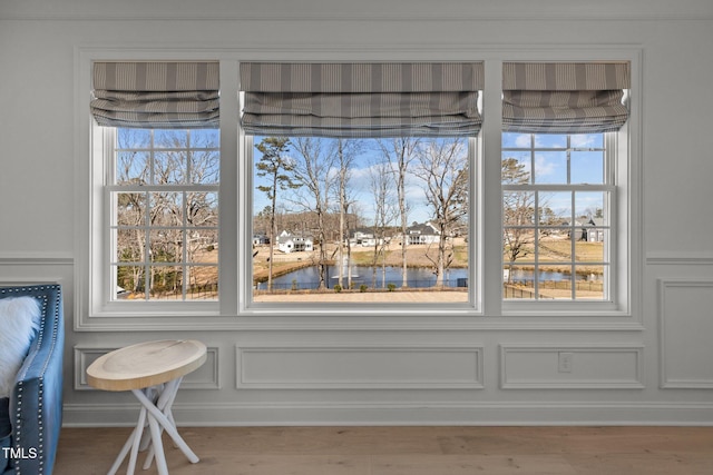 interior details with a water view, a decorative wall, and wood finished floors