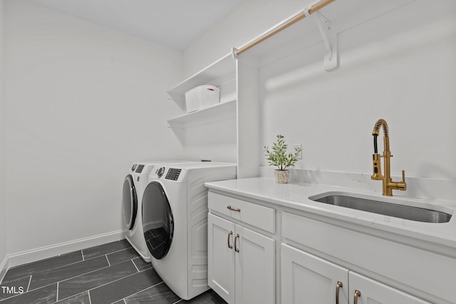 laundry room featuring baseboards, cabinet space, a sink, and washing machine and clothes dryer