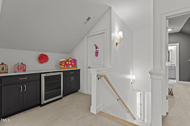 bar featuring wine cooler, light colored carpet, visible vents, vaulted ceiling, and a bar