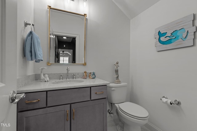 half bath with vanity, toilet, and baseboards