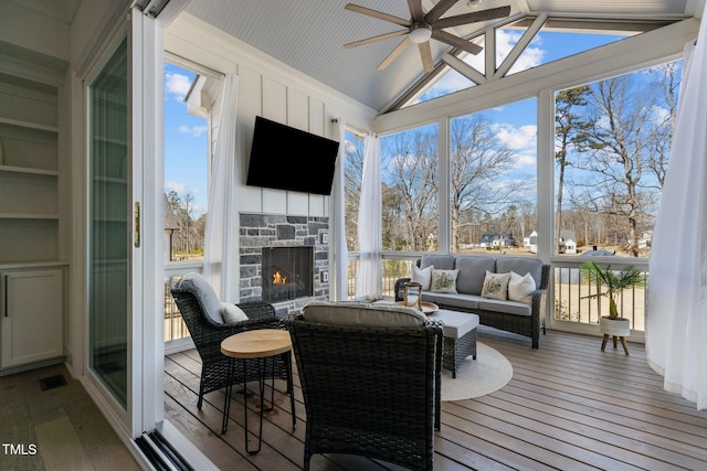 sunroom with lofted ceiling, visible vents, a fireplace, and a ceiling fan