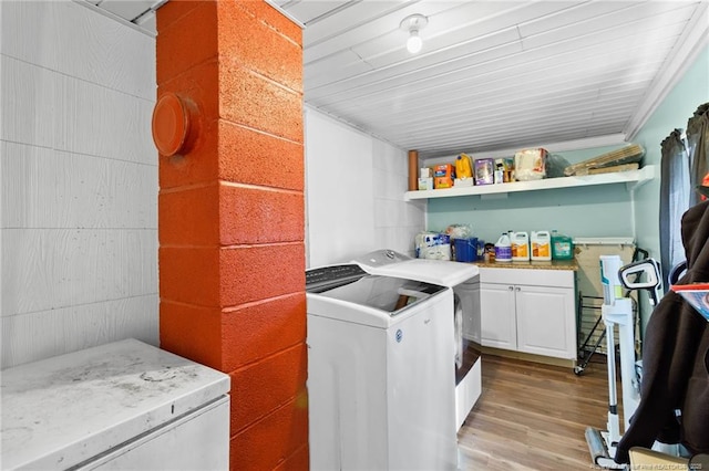 washroom with cabinets, washing machine and dryer, and light hardwood / wood-style floors