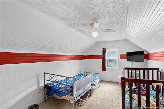 carpeted bedroom with lofted ceiling, a textured ceiling, and ceiling fan