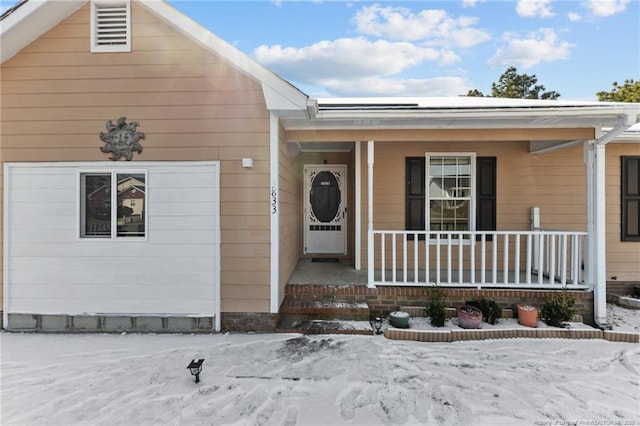 snow covered property entrance featuring a porch