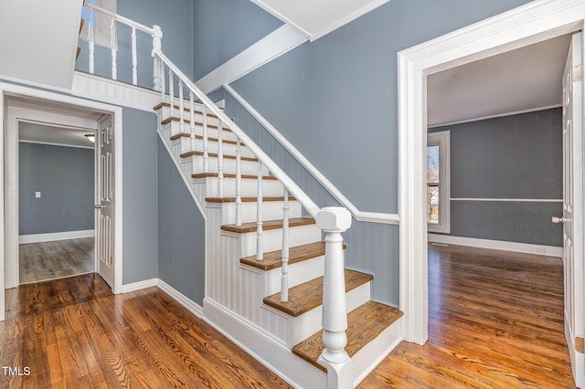 stairway featuring baseboards, ornamental molding, and wood finished floors