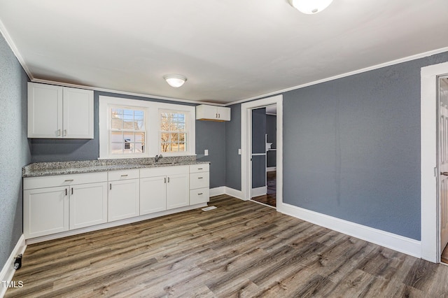 kitchen with hardwood / wood-style flooring, white cabinetry, and sink