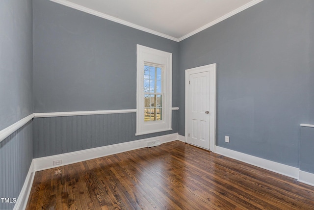 spare room with a wainscoted wall, dark wood-type flooring, visible vents, baseboards, and crown molding